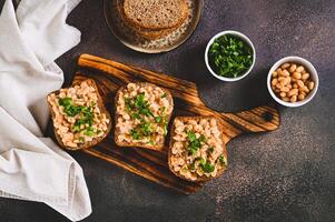 Appetizing sandwiches on grain bread with mashed beans and greens on a board top view photo