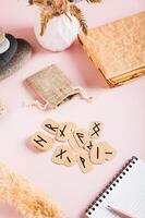 Cardboard Scandinavian runes for fortune telling on a pink background vertical view photo