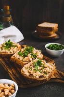Appetizing sandwiches on grain bread with mashed beans and greens on a board vertical view photo