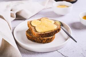 Morning sandwiches on grain bread with honey butter on a plate on the table photo