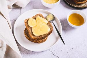 Delicious toasts with honey butter on a plate on the table photo