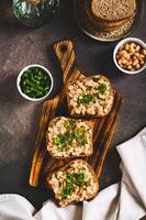 Bruschetta with mashed white beans and parsley on rye bread on a board top and vertical view photo