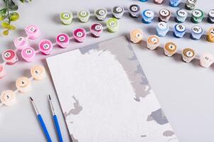 Paint by numbers painting, numbered paint containers and brushes on table photo