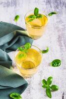 Refreshing summer basil lemonade with leaves in glasses on table vertical view photo