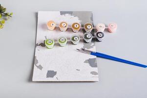 Unfinished paint by numbers painting and painting supplies on table photo