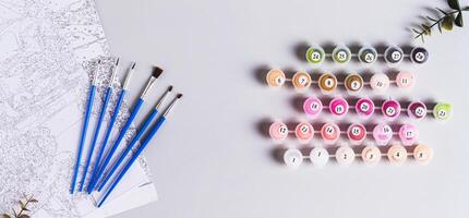 Acrylic paints, brushes and canvas for painting by numbers top view web banner photo