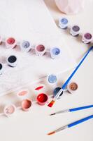 Brush dipped in red paint and containers with paints for painting a picture top and vertical view photo