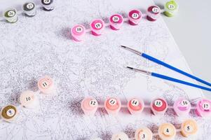 Paint containers, brushes and a paint by numbers chart on a table photo