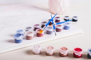 Brushes, multi-colored acrylic paints and canvas for painting by numbers on table photo