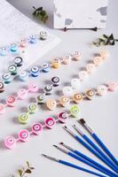 Acrylic paints, brushes and canvas for painting by numbers on the table vertical view photo