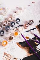 Set of multi-colored acrylic paints, brushes and canvas for painting by numbers vertical view photo