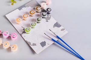Painting by numbers, paints and brushes on table for leisure photo