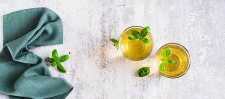 Refreshing summer basil lemonade with leaves in glasses on table top view web banner photo