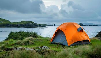Camping trip, orange tent on the shore of Irish island background wallpaper backdrop. Copy space, travel, outdoors activity, nature near a lake photo