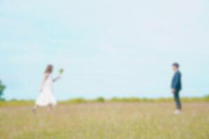 Blurred image of a couple running towards each other in a grass field, representing love and happiness photo