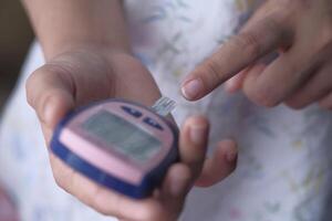 A person is using a glucometer in order to measure their blood sugar levels accurately photo