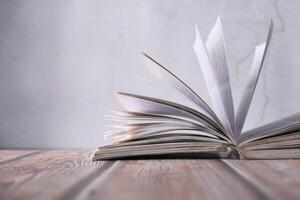 An Open Book Resting on a Wooden Table, Its Pages Seeming to Be in Motion and Dynamic photo