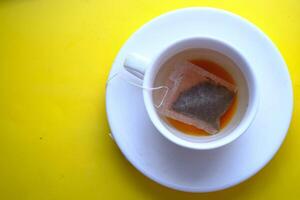 A lovely cup of tea brews on a bright yellow surface, creating an inviting atmosphere photo