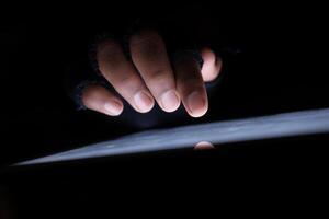 A CloseUp View of a Hand Engaging with a Tablet Screen in a Dimly Lit Environment photo