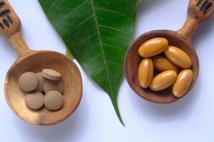 Natural Supplements Displayed in Wooden Spoons Against a Background of Green Leaves photo