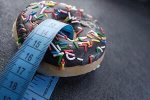 A delightful Chocolate Donut topped with colorful Sprinkles alongside a Measuring Tape photo