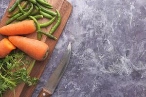Fresh vegetables artfully displayed on a wooden cutting board with a knife for prep photo