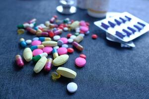 A Variety of Assorted Pills and Capsules Spilled Randomly on the Surface Below Them photo