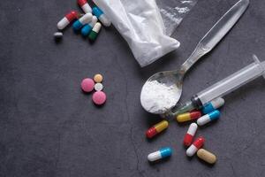 Various Assorted Pills and a Syringe Displayed on a Dark Surface for Medical Context photo