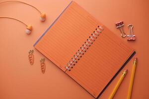 A Stylish Orange Notebook Complete with Stationery Accessories Laid Out on a Vibrant Background photo