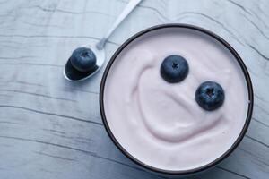 A delightful and playful yogurt bowl topped with fresh blueberries and a cheerful smiley face photo