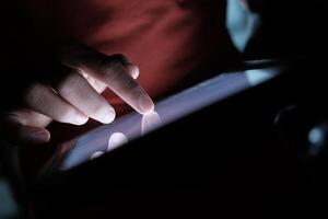 A CloseUp of a Hand Engaging with a Tablet in Subdued Low Light Conditions and Settings photo