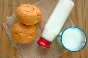 Enjoying fresh milk alongside delightful bread rolls presented on a rustic wooden table photo