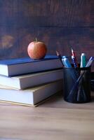 Necessary Study Supplies A Collection of Books, an Apple, and Various Writing Tools on a Desk Table photo