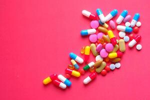 A Colorful and Diverse Assortment of Various Pills and Capsules Displayed on a Red Background photo