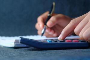 Hands Using a Calculator and Writing Notes on a Sheet of Paper for Better Understanding photo