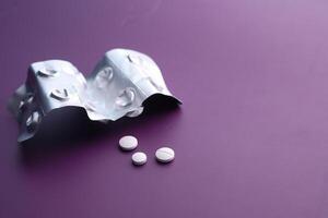 A Blister Pack of Various Medications with Colorful Pills on a Vibrant Purple Background photo