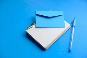 Aesthetic stationery setup on a blue background with a notebook and envelope for creativity photo