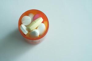 An assortment of colorful pills organized neatly in an orange container on a light background photo