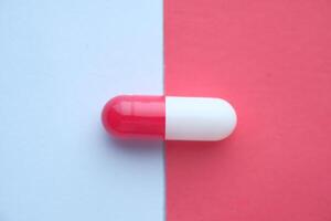 A Red and White Capsule Resting on a Vibrantly Colorful Background Displays its Appeal photo