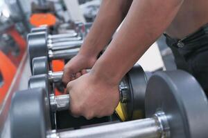 Closeup image of hands gripping dumbbells in a gym, showcasing fitness enthusiasm and strength photo