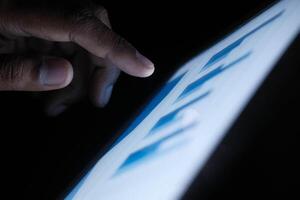 A person is interacting with a tablet screen in a low light environment, utilizing touch photo