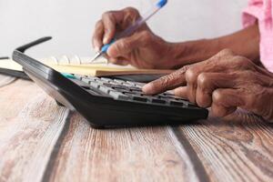 A Person Using a Calculator and a Notepad for Detailed Financial Calculation and Analysis photo