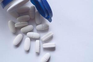 A Detailed CloseUp Image Showing the Spill of White Pills from a Blue Container photo