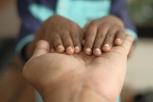 A childs small hands are resting gently and lovingly on the larger hand of an adult photo