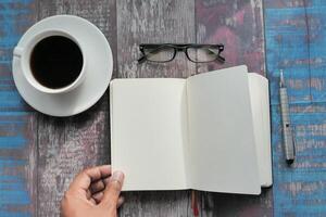 A creatively designed workspace featuring a cup of coffee, stylish glasses, and an open notebook photo