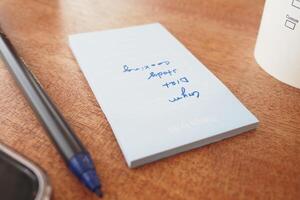 To do list in notebook with office suppliers on desk. photo