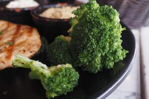 A Delicious Plate of Fresh Broccoli Accompanied by Juicy Grilled Chicken and Various Sides photo