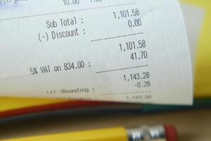 A receipt, coins, and a pencil on a table symbolize finance, transactions, and commerce photo