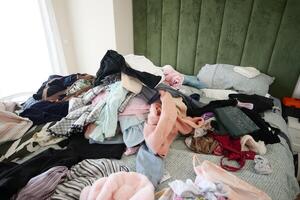 A Messy Bed with Various Colorful Clothes and Soft Pillows Is a Cozy and Casual Space photo
