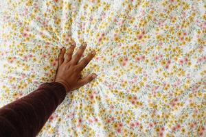 A closeup view of a hand gracefully resting on a beautifully floral patterned fabric surface photo